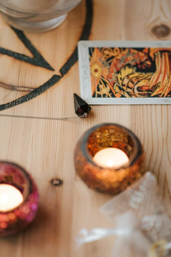 From above of shiny candles in decorative holders near tarot card and talisman during divination process